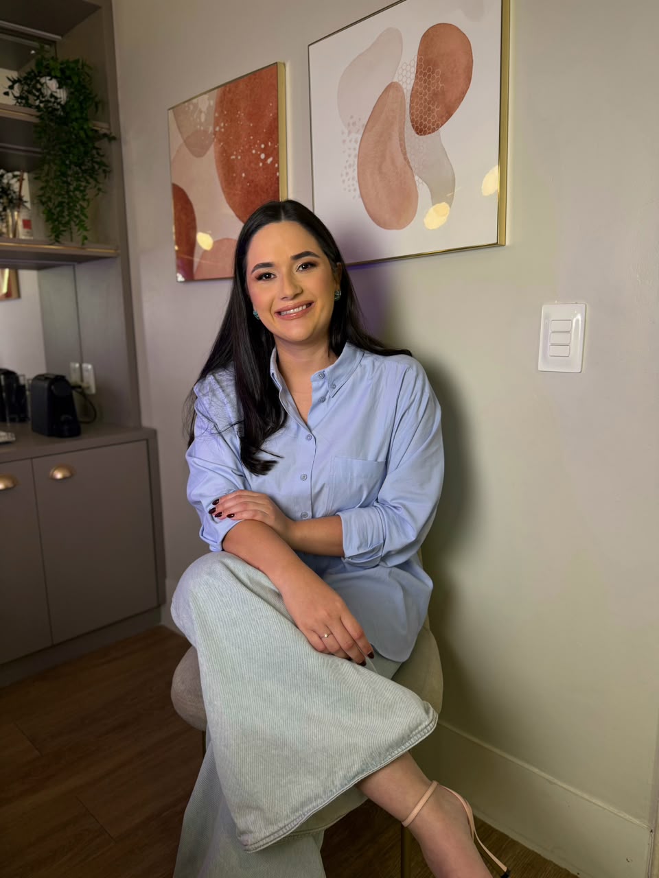 Dra. Larissa Costa sentada na cadeira, com as pernas cruzadas